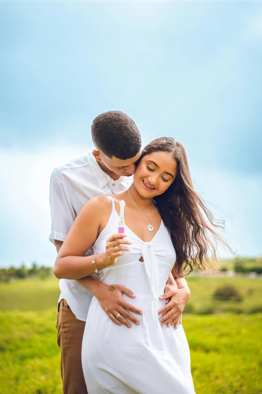 a couple emcing in the grass with the sky in the background