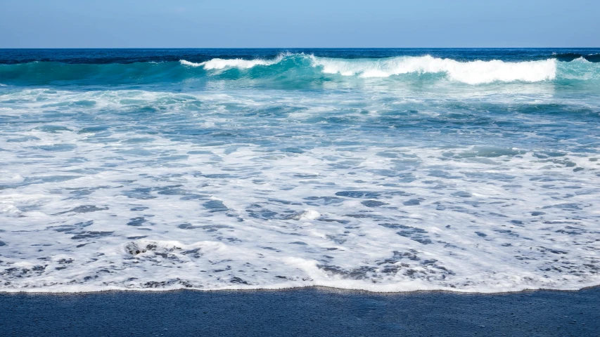 a view of some ocean waves with the blue sky in the background