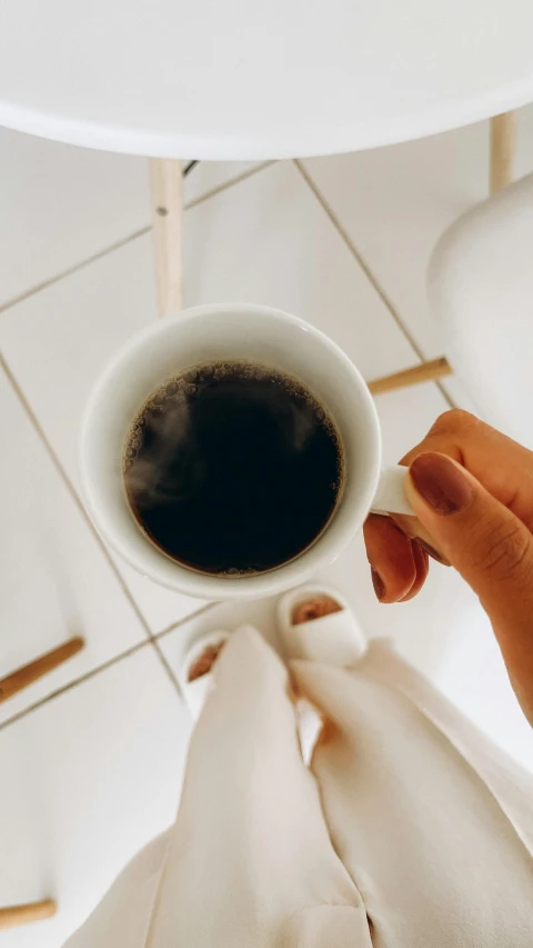 someone holding a coffee cup over their left hand