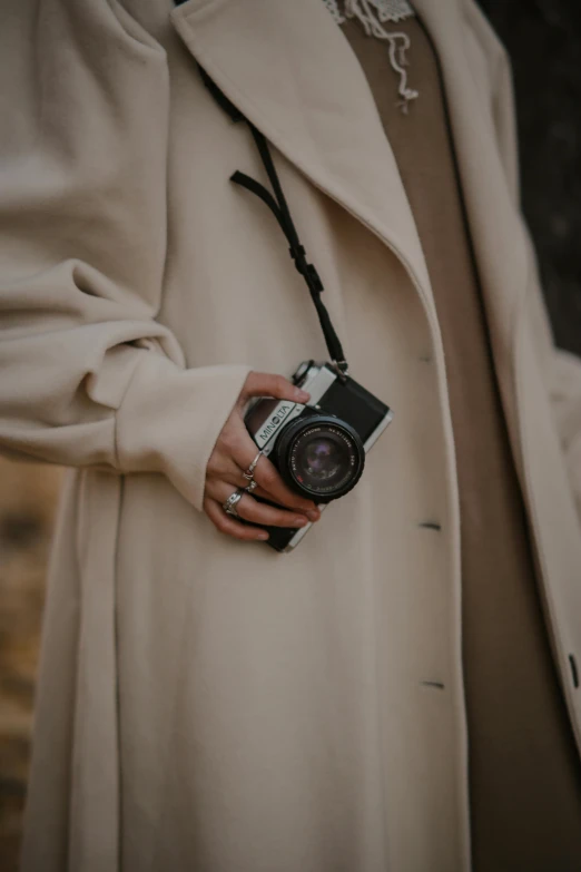 a woman in a coat is holding up a camera