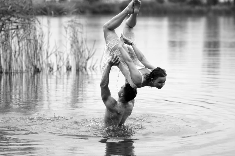 two people holding up one another while standing in a lake