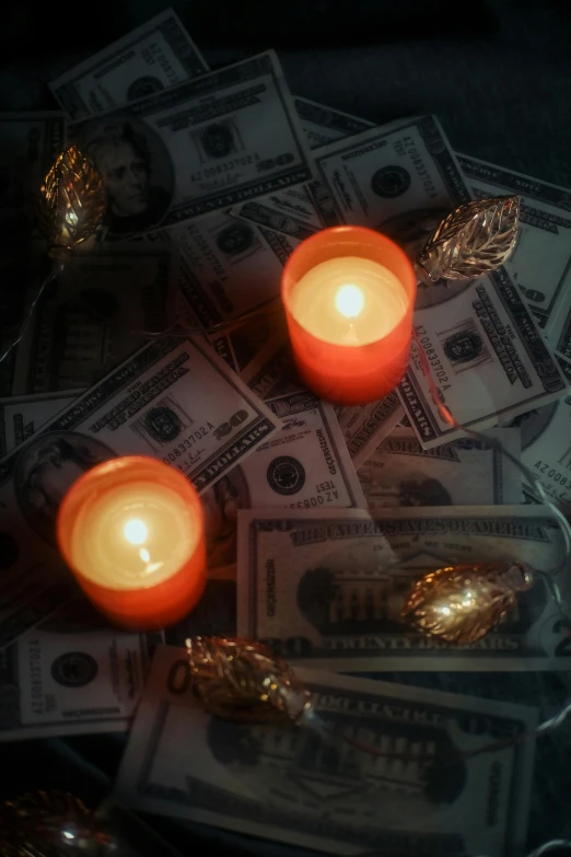 a tray holding money and two lit candles on top of it