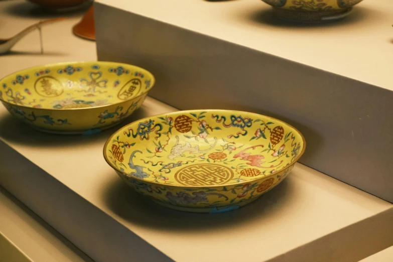 yellow bowls with designs on them are sitting on a shelf