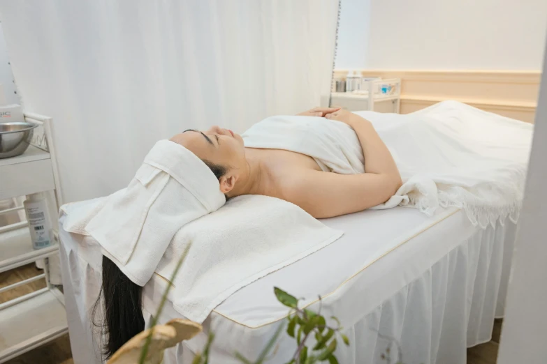 a woman laying on a white bedspread in a room