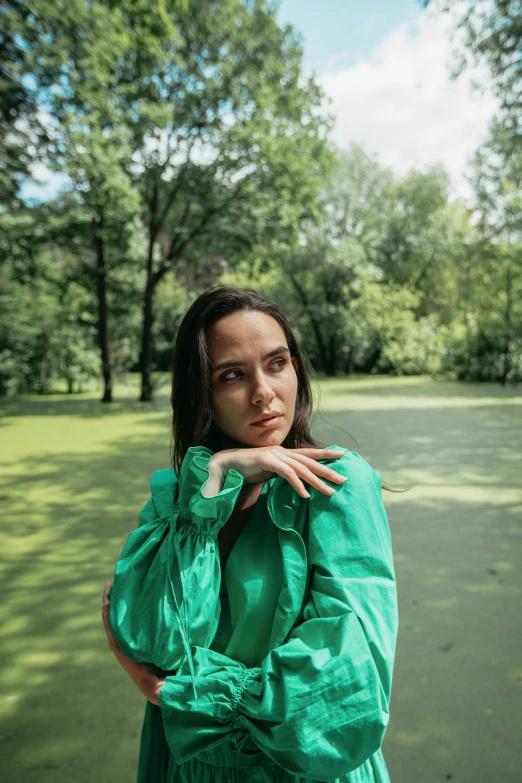 a woman wearing a green dress standing in a field