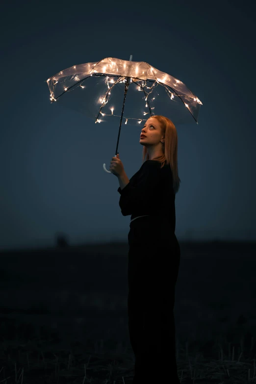 a woman holding an umbrella and standing with fairy lights