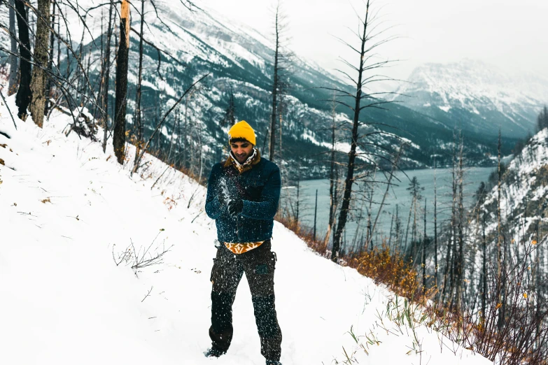 a man stands in the snow on skis near a mountain