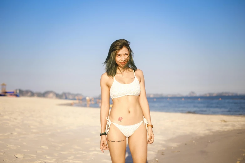 the woman is wearing a bikini and standing on the beach