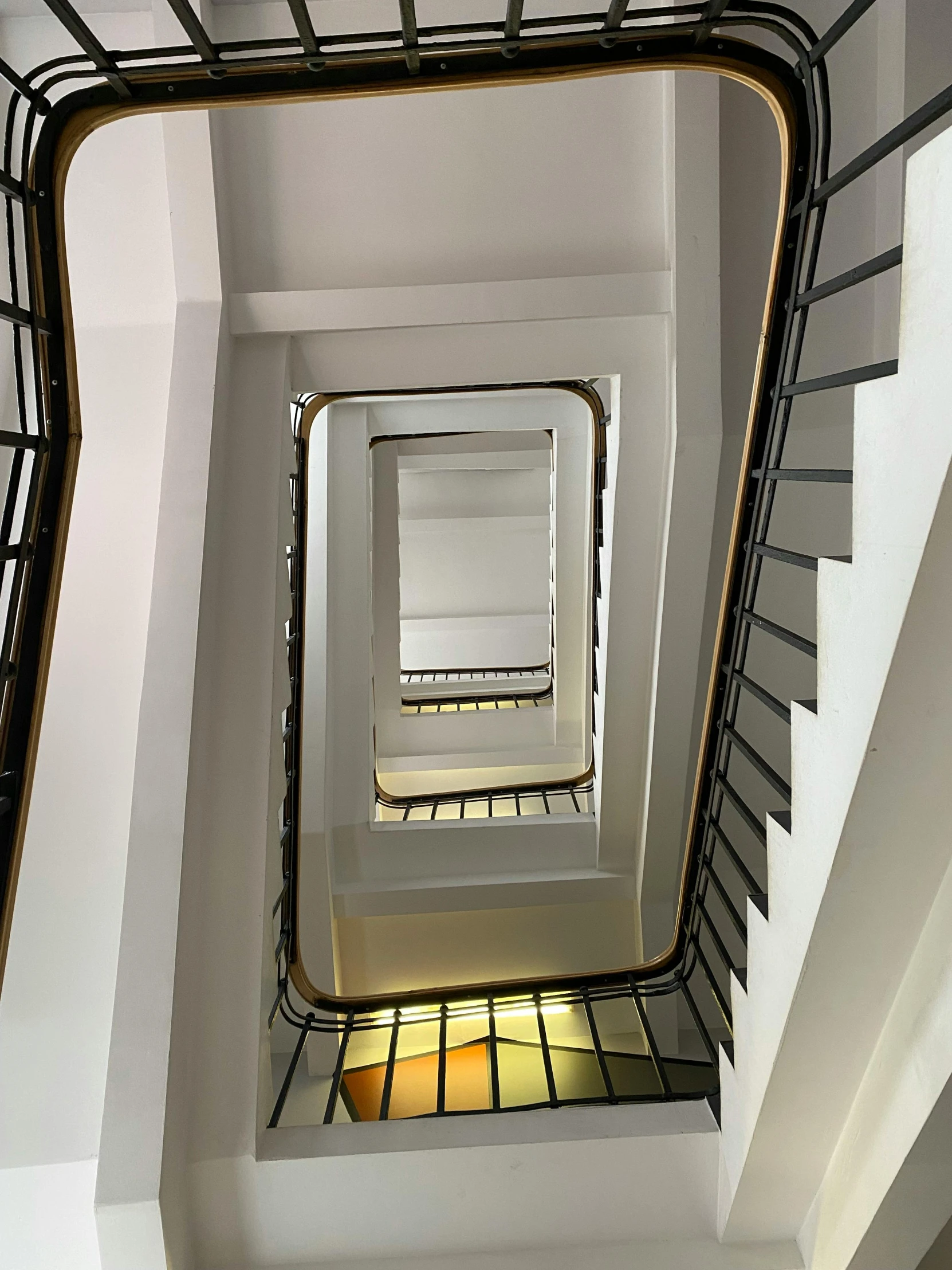 the ceiling in the stairwell is mostly white and has many windows