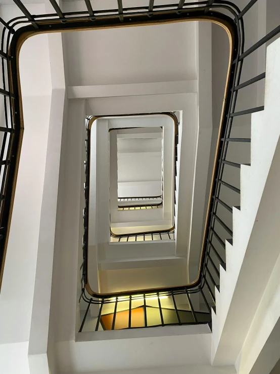 the ceiling in the stairwell is mostly white and has many windows