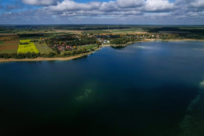 a small, lake near a town with the sun shining on it