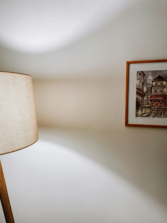 the floor lamp is standing next to a painting on the wall