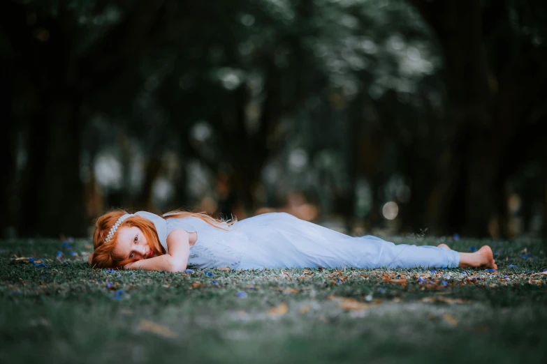 a girl laying on the ground in white dress