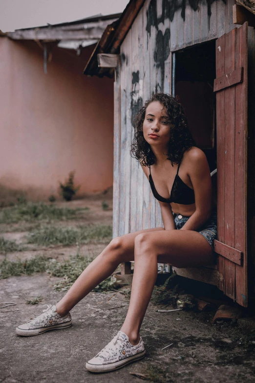 a woman sitting on the side of a brown building