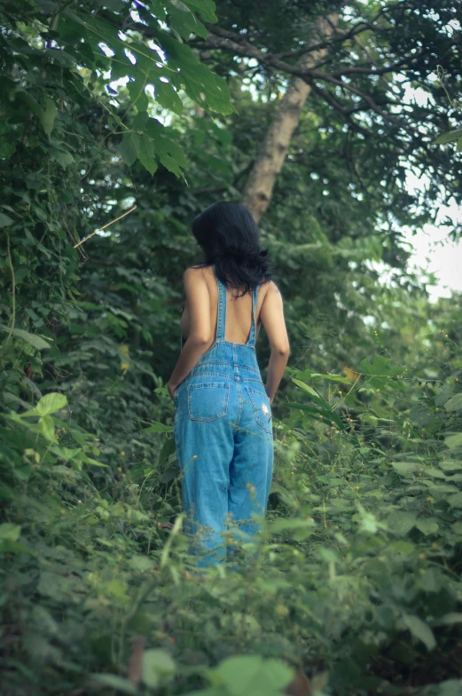 a woman wearing blue jeans standing on a lush green field