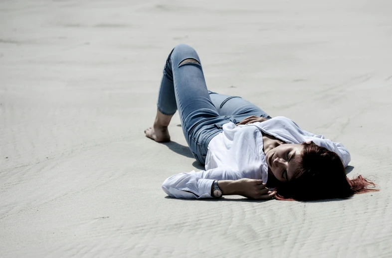 a woman is laying on her stomach down on the beach