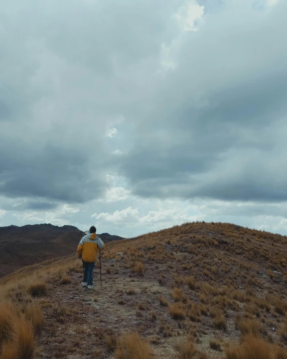 a man standing on the top of a hill under a cloudy sky