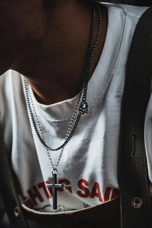 a person wearing a t - shirt with a chain with a cross on it