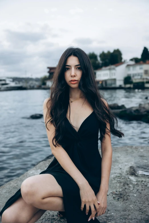 a girl is sitting on the edge of a dock and posing