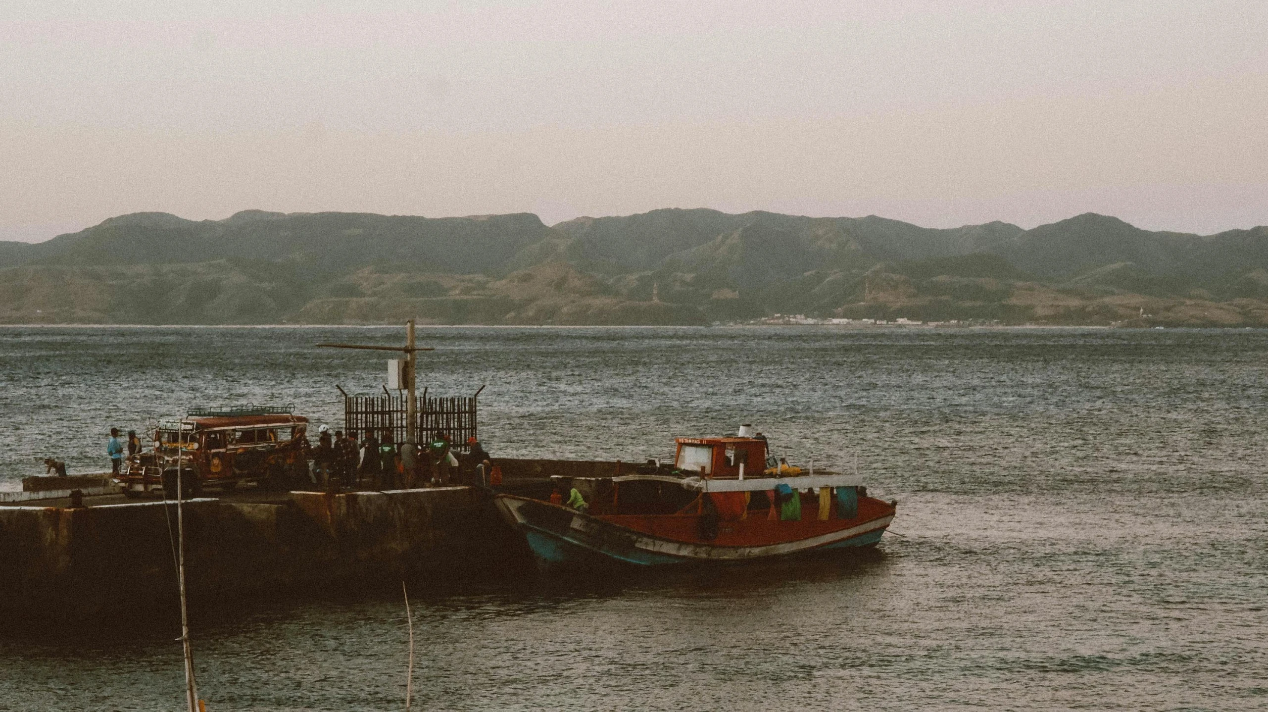 a ship is sitting out in the water with mountains in the background