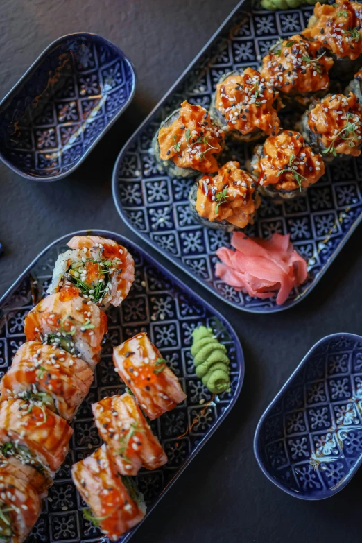 three trays with sushi and one plate containing meat