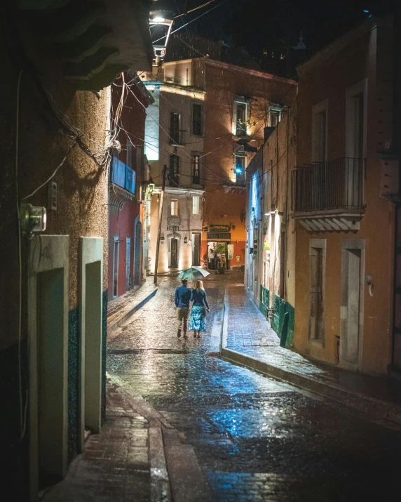 two people walking down a rainy street carrying umbrellas