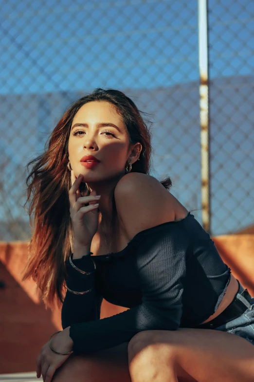 a beautiful young woman leaning on a fence