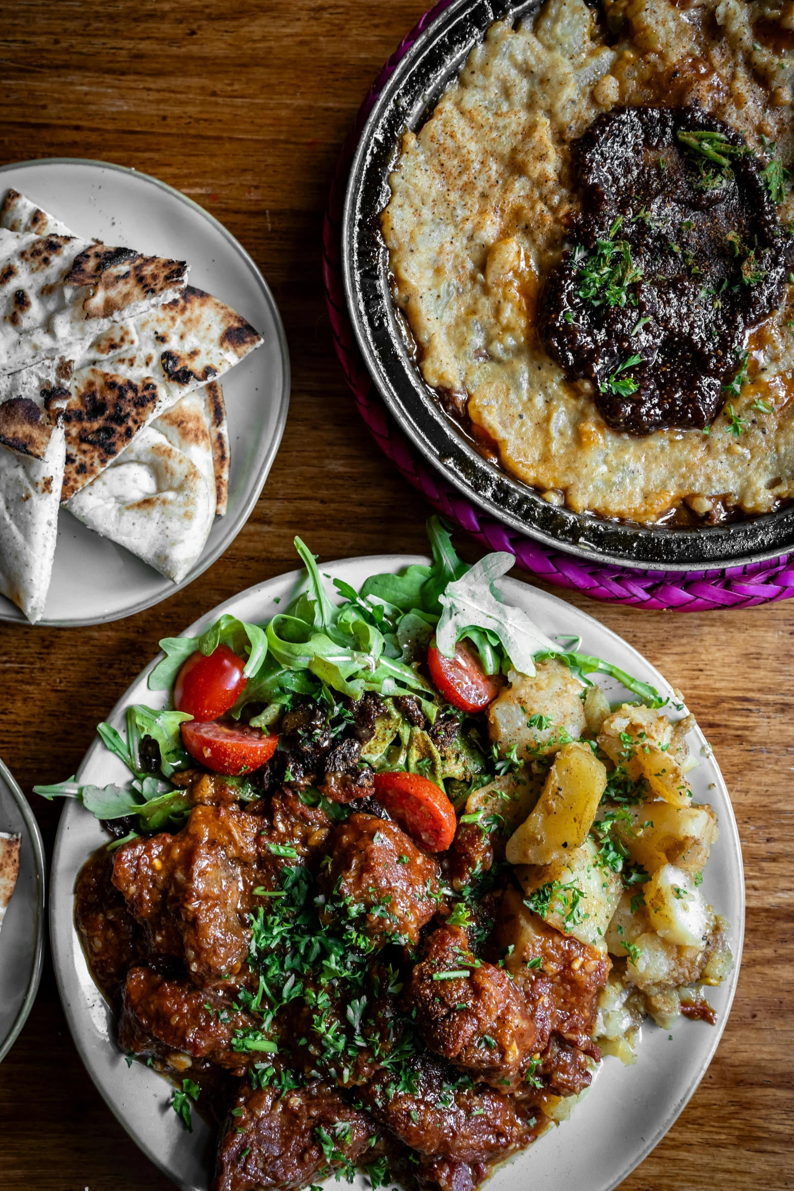 a plate of meat and vegetables and some pita bread