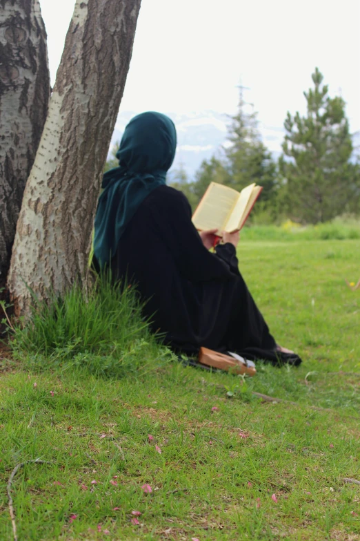 the person wearing the green head scarf is reading a book