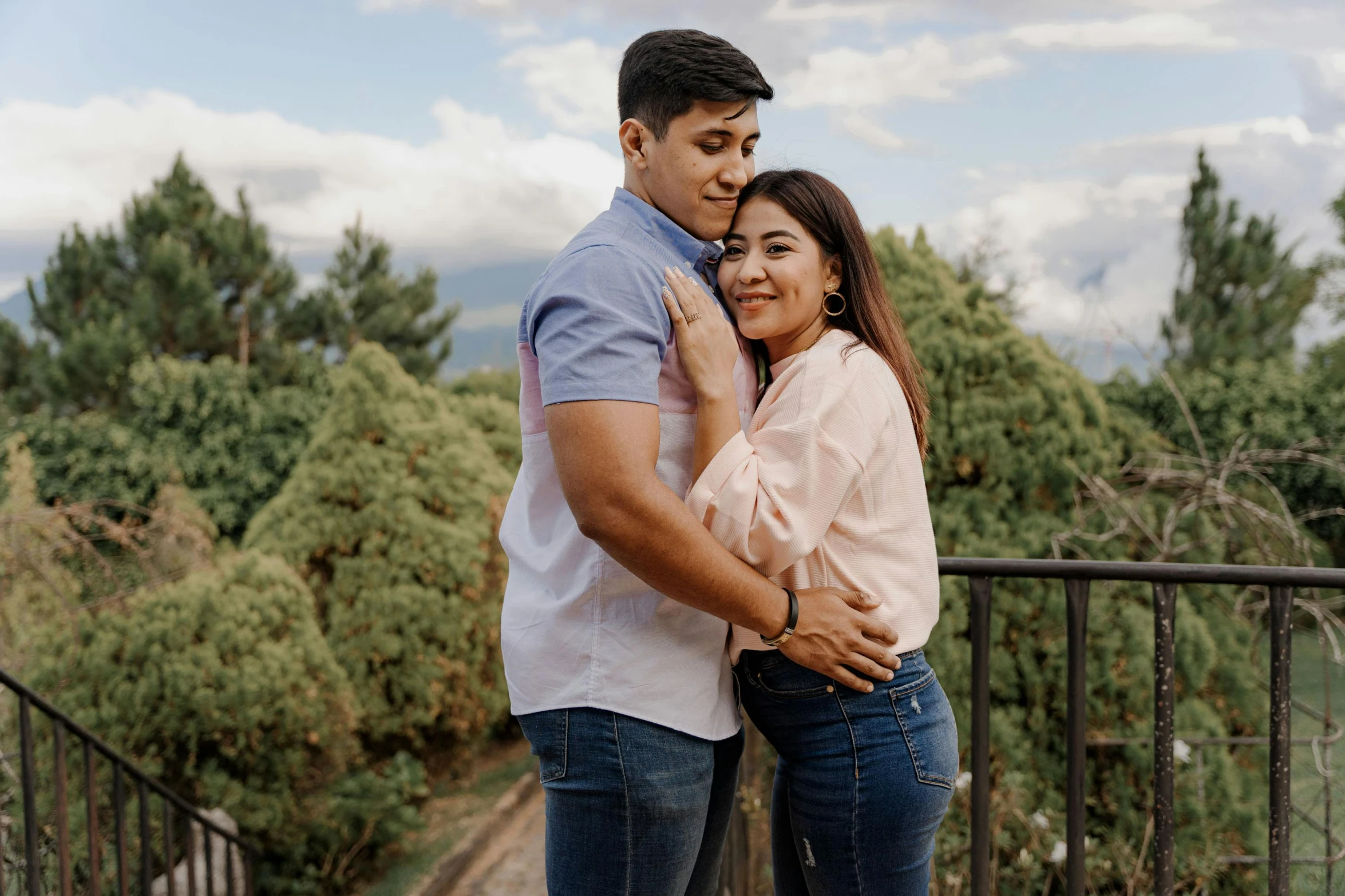 a man and woman emcing in front of trees