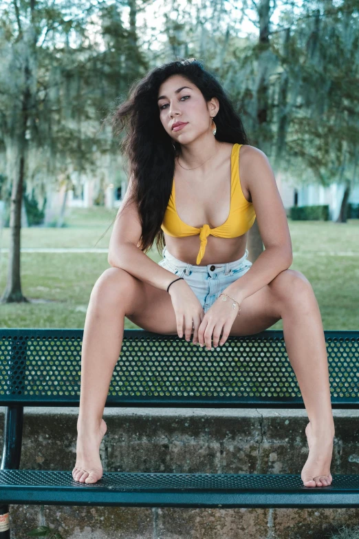 a pretty young lady in a yellow top posing for the camera
