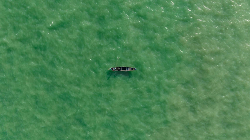 a lone small boat floating in the green water