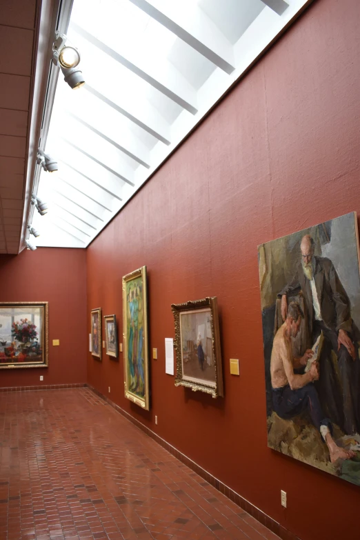 the red wall shows several paintings of people