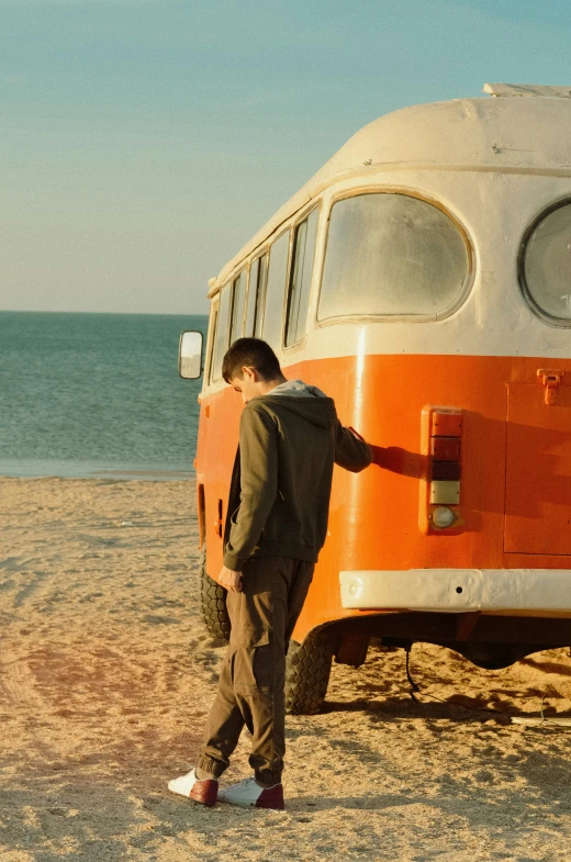 a man standing next to an orange and white bus