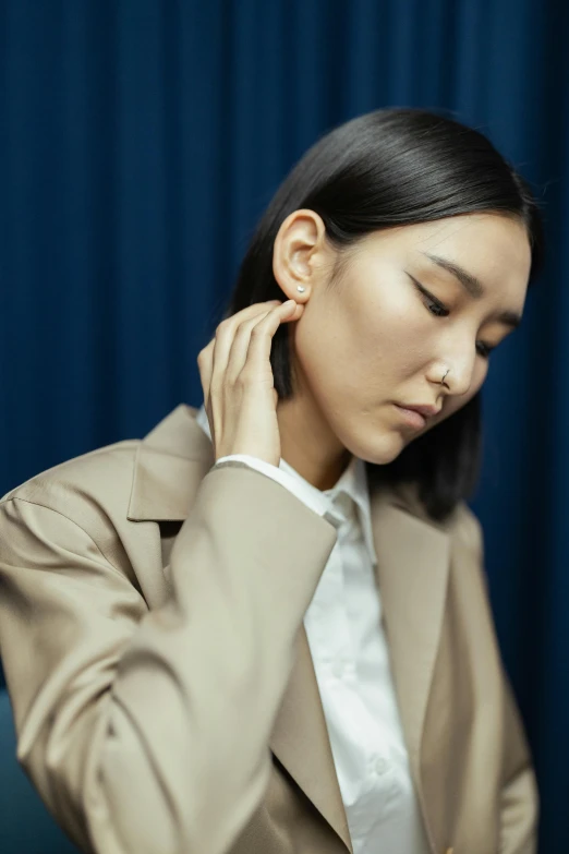 an asian woman in business attire is touching the ear