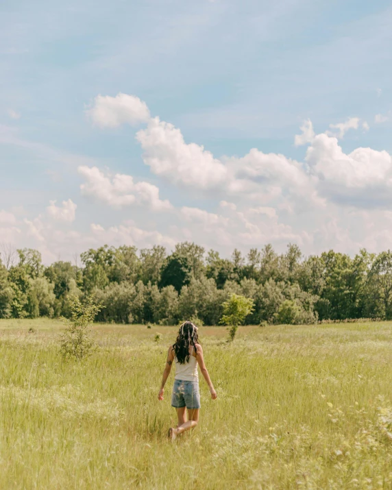 there is a girl that is walking through the grass