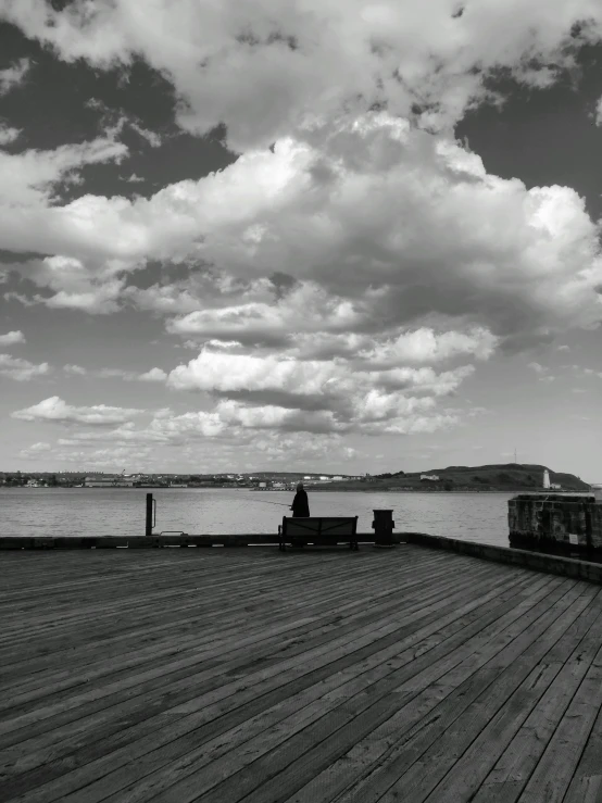 this black and white po shows clouds over a pier