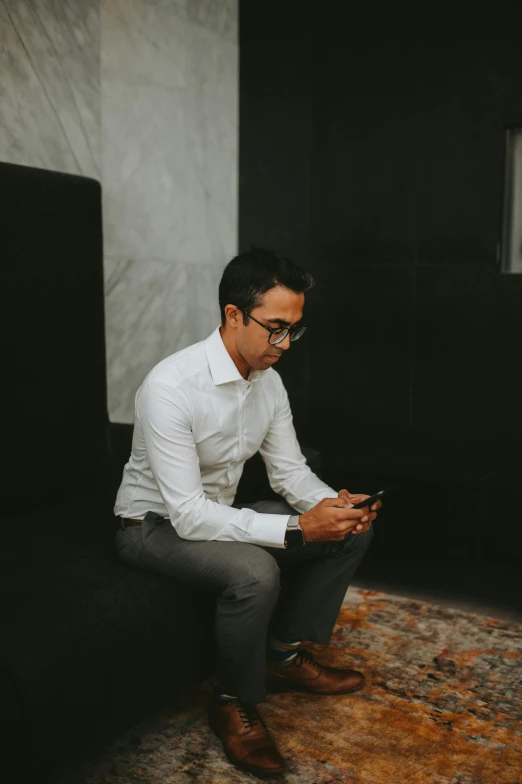 a young man sitting on a couch looking at his phone