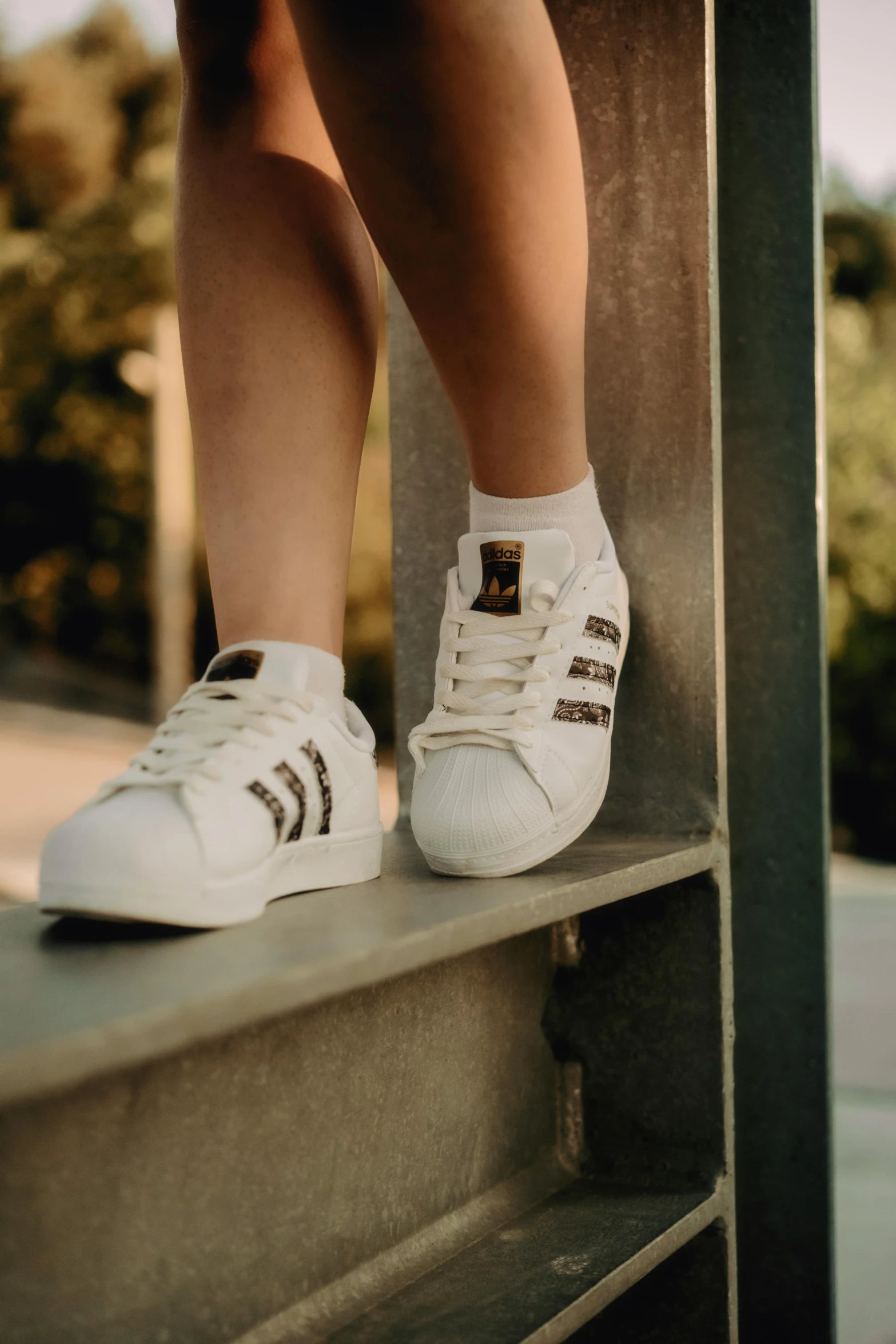 a person wearing white sneakers stands on a ledge