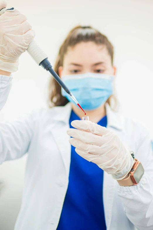 a woman wearing white gloves and surgical gear with a blue surgical mask on