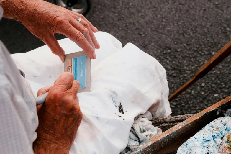 the hands of an old man with a small box