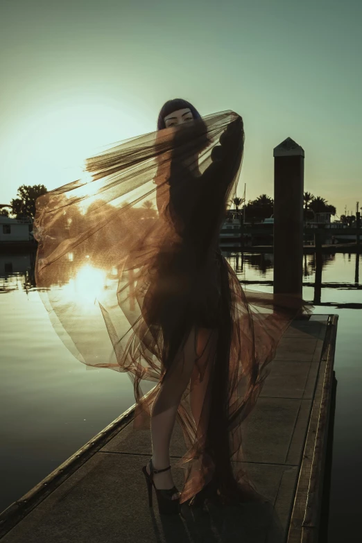 a woman is leaning against a dock at sunset