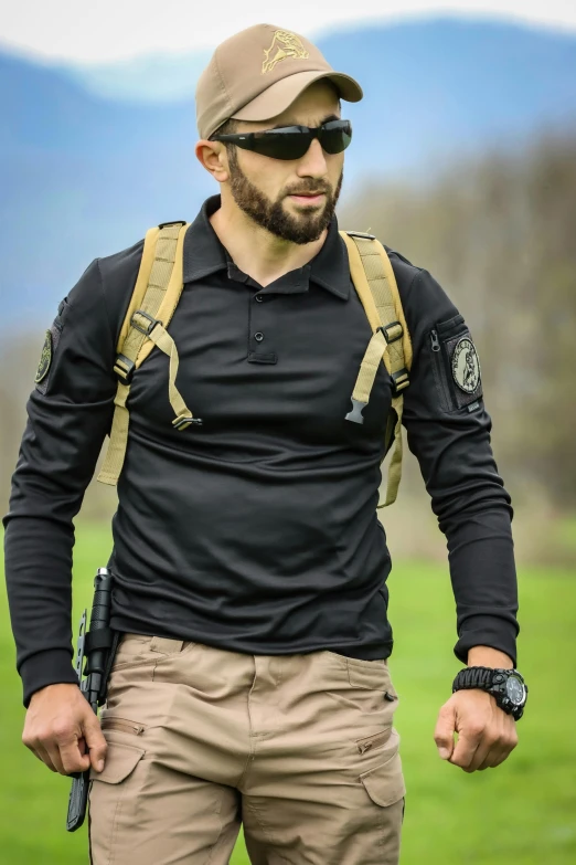 a man wearing sunglasses and a backpack is walking in a field