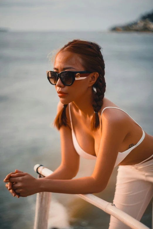 a woman in sunglasses standing by the water