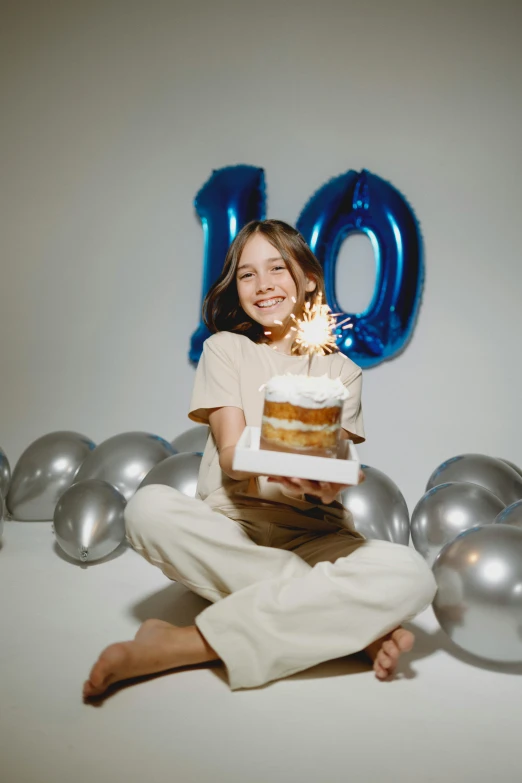 a young woman in front of balloons and a cake