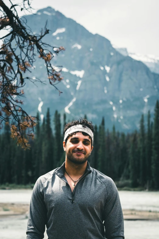 man posing in front of mountain in front of water and trees