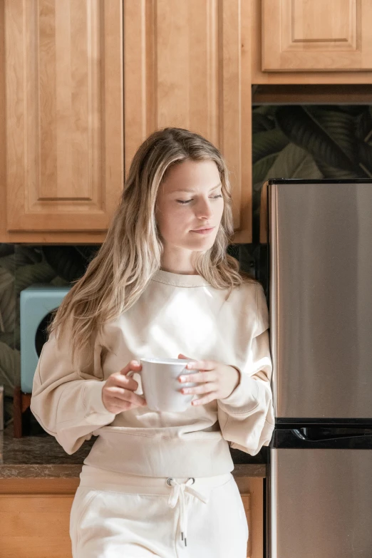 a woman in a bathrobe is standing next to the fridge