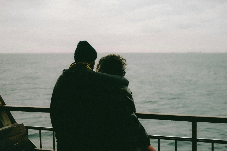 a man and woman sitting on a bench overlooking the water