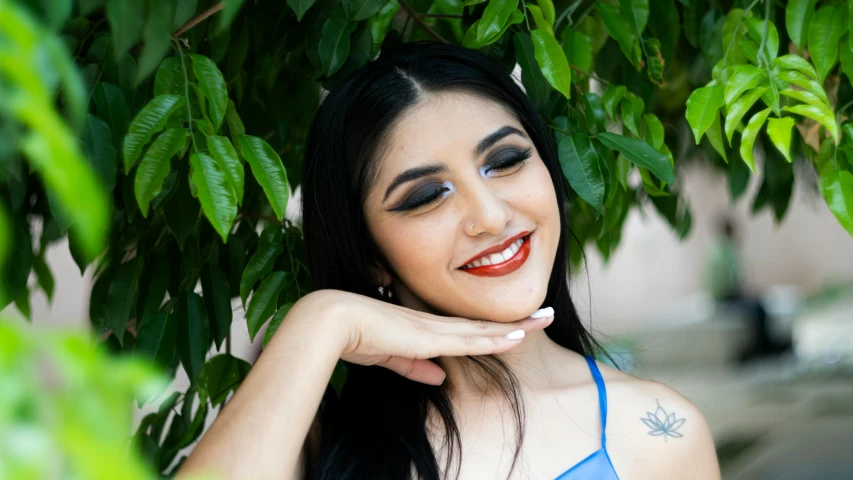 a young lady posing in front of a tree