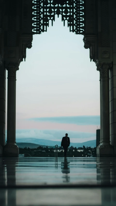 a man walking by an archway looking over the water